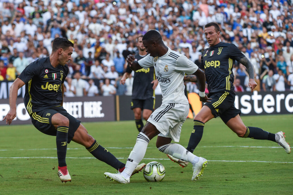 Vinicius Junior driblando adversarios com a camisa do Real Madrid em partida contra a Juventus