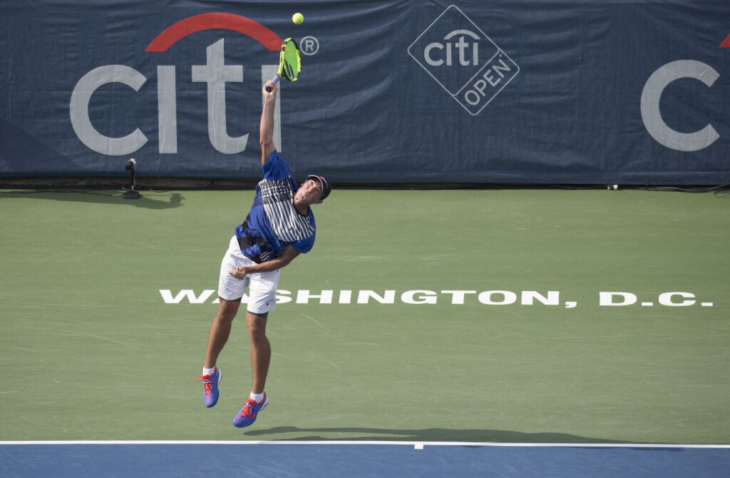 Tenista salta e saca durante partida em quadra dura no Citi Open, em Washington