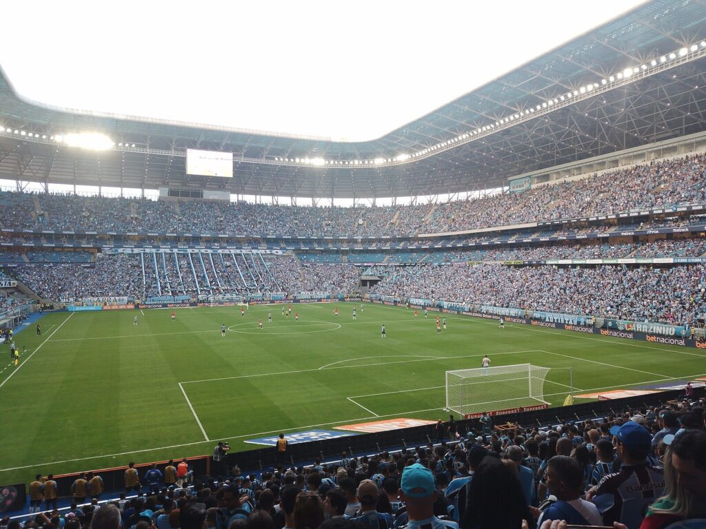 Estádio de futebol lotado durante partida do Brasileirão, com jogadores em campo e arquibancadas cheias (Foto de arquivo: partida do Brasileirão de 2024 na Arena do Grêmio, sem relação direta com os times atualmente na zona de rebaixamento.)