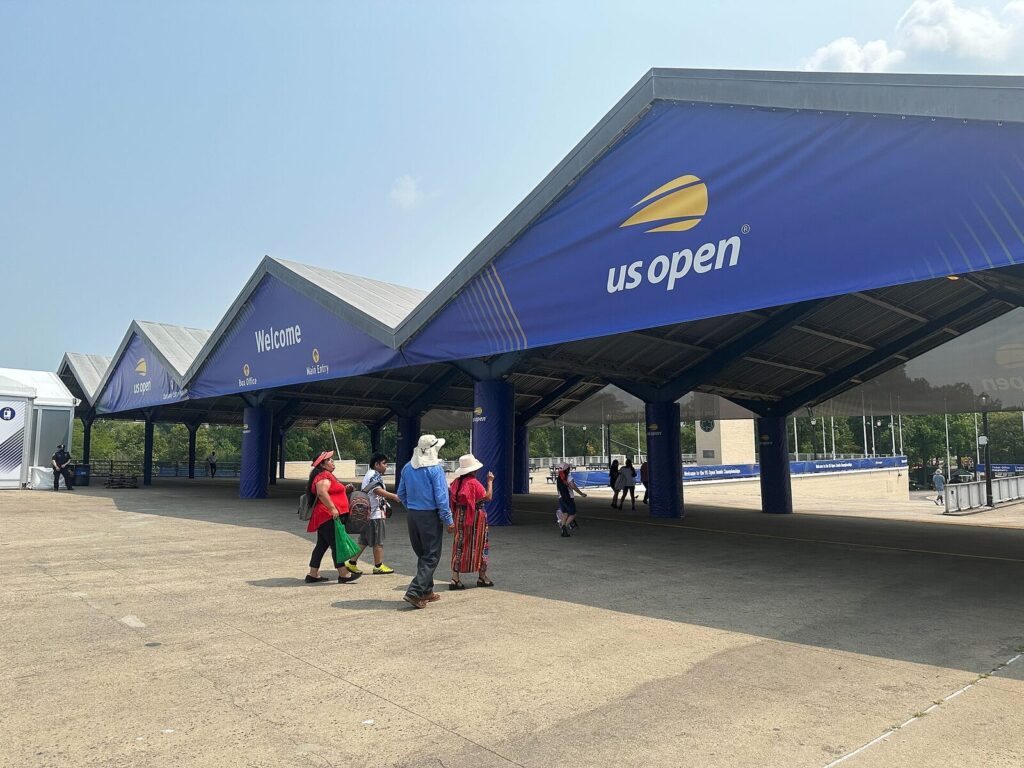 Entrada do US Open no Billie Jean King National Tennis Center com faixas azuis de boas-vindas (Foto de arquivo: entrada do US Open no Billie Jean King National Tennis Center, 2024.)