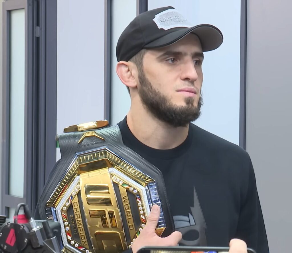 Islam Makhachev posa com o cinturão do UFC em foto de arquivo, boné preto e camiseta preta