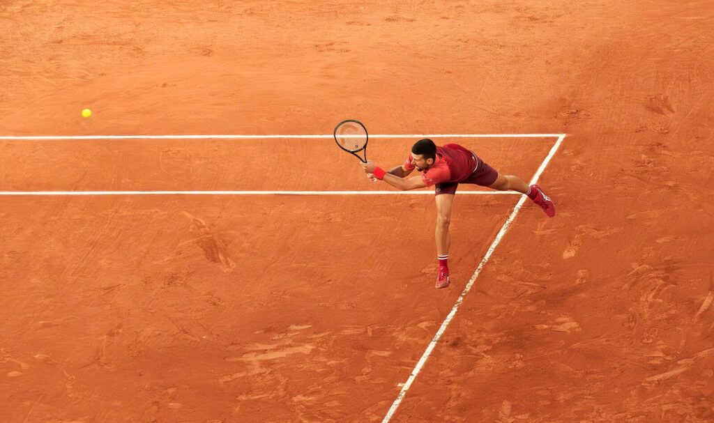 Novak Djokovic rebatendo de backhand durante partida de primeira rodada em Roland-Garros, maio de 2024. (Foto de arquivo: Djokovic em Roland-Garros, maio de 2024.)