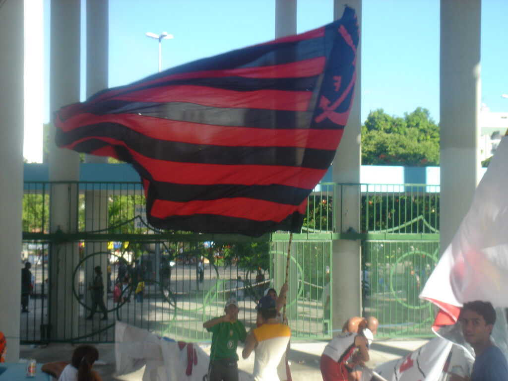 Torcedor do Flamengo com bandeira do clube em frente a portão de estádio (Foto de arquivo: torcedor do Flamengo com bandeira do clube, 2006.)