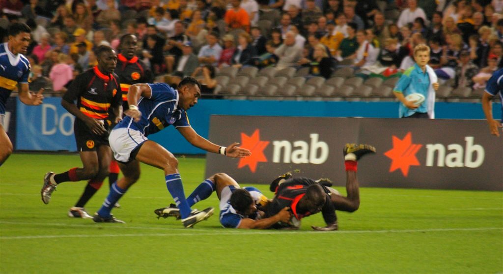 Jogador de Uganda mergulha para marcar um try contra Samoa em partida de rugby sevens (Foto de arquivo: try marcado em partida de rugby sevens Uganda x Samoa, Jogos da Commonwealth de 2006.)