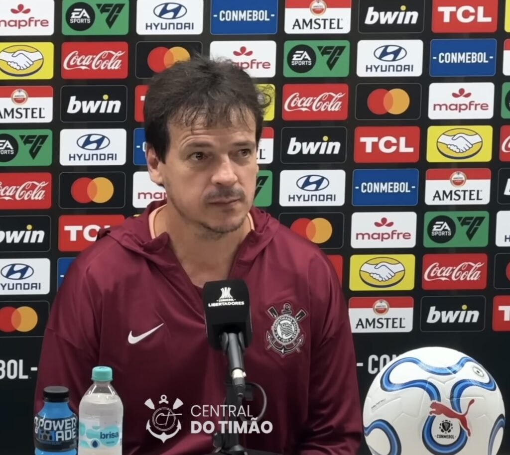 Técnico em coletiva de imprensa com backdrop oficial da Conmebol Libertadores 2026