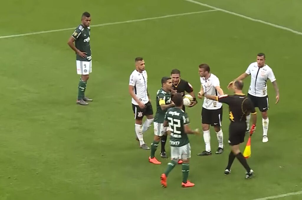 Jogadores do Palmeiras e do Corinthians reunidos em campo ao redor do árbitro em clássico paulista (Foto de arquivo: Palmeiras e Corinthians em confronto válido pelo Campeonato Paulista de 2018, não a partida atual.)