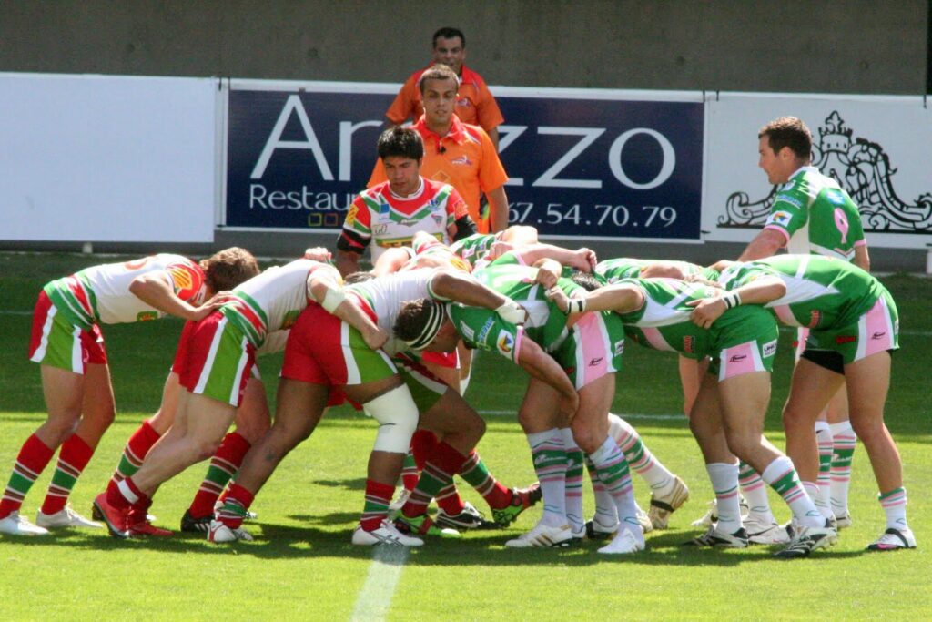 Jogadores formando um scrum durante partida de rugby (Imagem genérica de um scrum de rugby, sem relação com uma partida específica, ilustra a dinâmica do jogo mencionada no texto.) (Imagem genérica de um scrum de rugby, sem relação com uma partida específica, ilustra a dinâmica do jogo mencionada no texto.) (Imagem genérica de um scrum de rugby, sem relação com uma partida específica, ilustra a dinâmica do jogo mencionada no texto.)