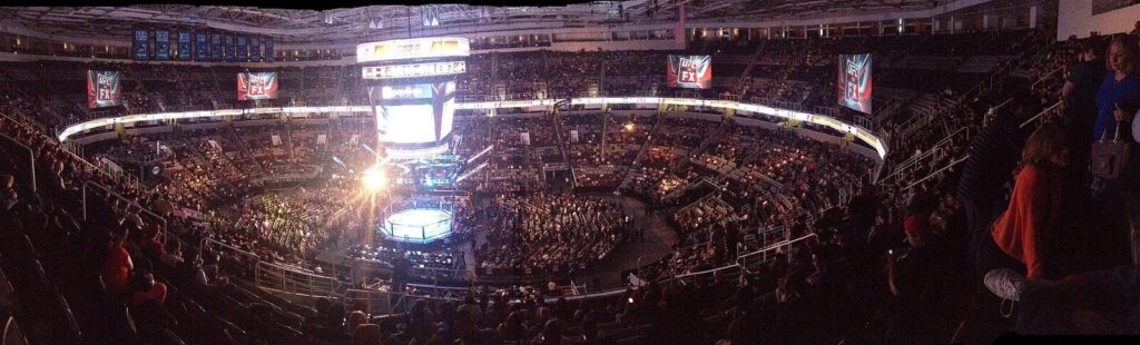 Vista panorâmica de arena lotada durante evento do UFC, com octógono iluminado ao centro (Foto de arquivo: evento do UFC em San Jose (2013), sem relação direta com a luta entre Buckley e Malott no UFC Fight Night 291.)